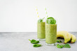 Green smoothie with banana and spinach or other green vegetables and fruits. Gray light background