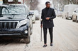 © AS Photo Family - Stylish african american gentleman in elegant black jacket, holding retro walking stick with golden diamond ball handle. Rich fashionable afro man against business suv car.