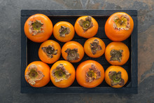Top View Of Orange And Whole Persimmons In Wooden Box