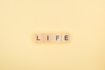 top view of life lettering made of wooden cubes on yellow background