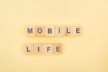 Wall Mural - top view of mobil life lettering made of wooden cubes on yellow background