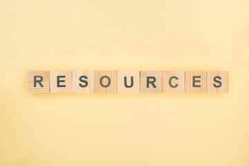 Wall Mural - top view of resources lettering made of wooden cubes on yellow background