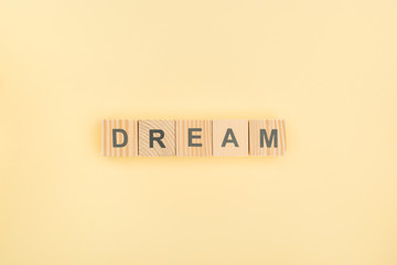 Wall Mural - top view of dream lettering made of wooden cubes on yellow background