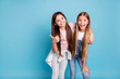 © deagreez - Portrait of two people nice cute lovely charming dreamy attractive cheerful straight-haired pre-teen girls siblings showing aside ad promotion copy space isolated on blue turquoise background