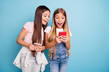 Sticker - Close up photo two people little she her blond brunette girls long pretty hair telephone hands arms look open mouth wow face wearing casual jeans denim t-shirts isolated blue bright background