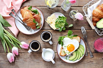 Breakfast food table. Festive brunch set, meal variety with fried egg, croissant sandwich, granola and smoothie. Overhead view