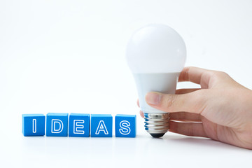 Wall Mural - Blue color ideas word next to a light bulb isolated on black background