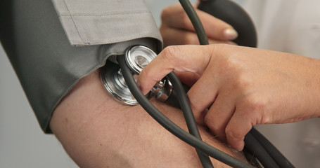 Wall Mural - Extreme close up on stethoscope and blood pressure cuff on arm as doctor checks older male patient using sphygmomanometer