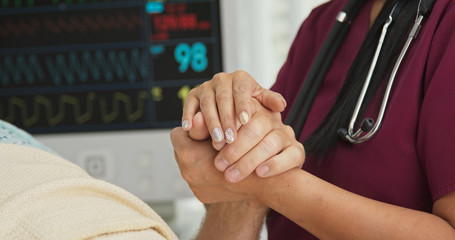 Wall Mural - Close up on hands of doctor or nurse comforting man in hospital bed. Woman with bejeweled nails holding hand of recovering patient