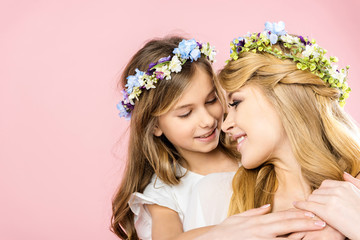 Wall Mural - adorable smiling child embracing beautiful happy mother on pink background