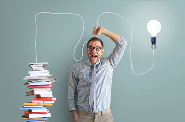 Wall Mural - Young man smiles and holds a bright light bulb on the wire