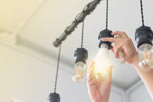LED Light Power Saving Concept. Asia Man Changing Compact-fluorescent (CFL) Bulbs With New  Bulb.