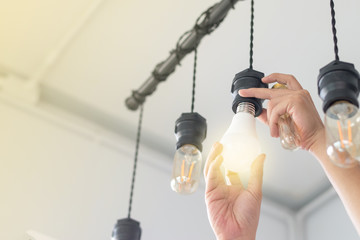led light power saving concept. asia man changing compact-fluorescent (cfl) bulbs with new bulb.