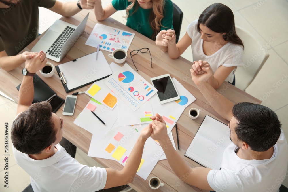 Group of people praying before meeting in office