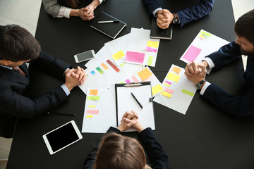 Group of people praying before meeting in office