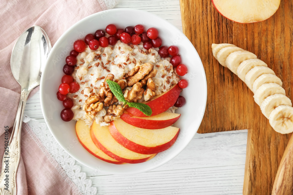 Bowl with tasty oatmeal on white table