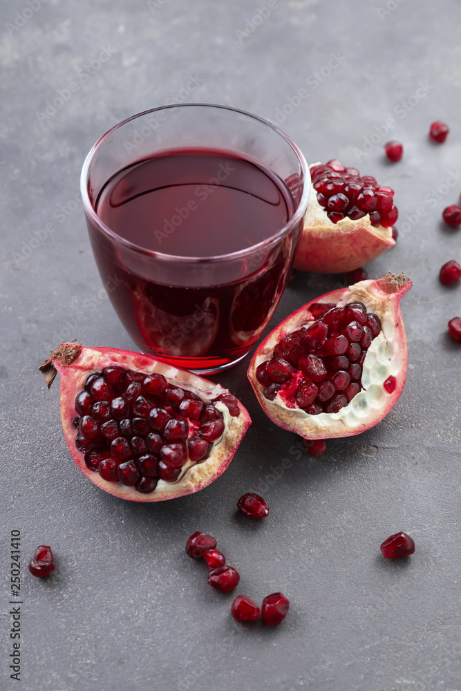 Glass of fresh pomegranate juice on grey background