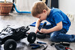 © Aboltin - Auto modeling: little boy repairing a model radio-controlled car at home.
