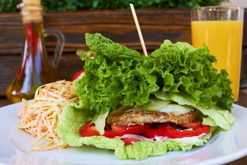 Wall Mural -  green burger. lettuce, greens, tomatoes, peppers, carrots. healthy food. In the background is a glass bottle of olive oil, green and red peppers, onions, tomato and garlic.