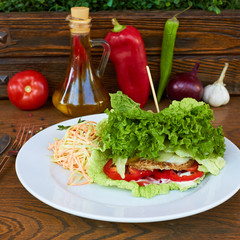 Wall Mural -  green burger. lettuce, greens, tomatoes, peppers, carrots. healthy food. In the background is a glass bottle of olive oil, green and red peppers, onions, tomato and garlic.