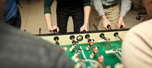 Guy is  playing table soccer indoor