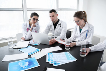 Canvas Print - Team of doctors discussing diagnosis at table in clinic