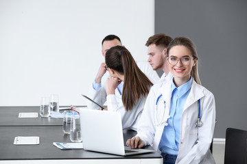 Canvas Print - Young doctors sitting at table during meeting in clinic