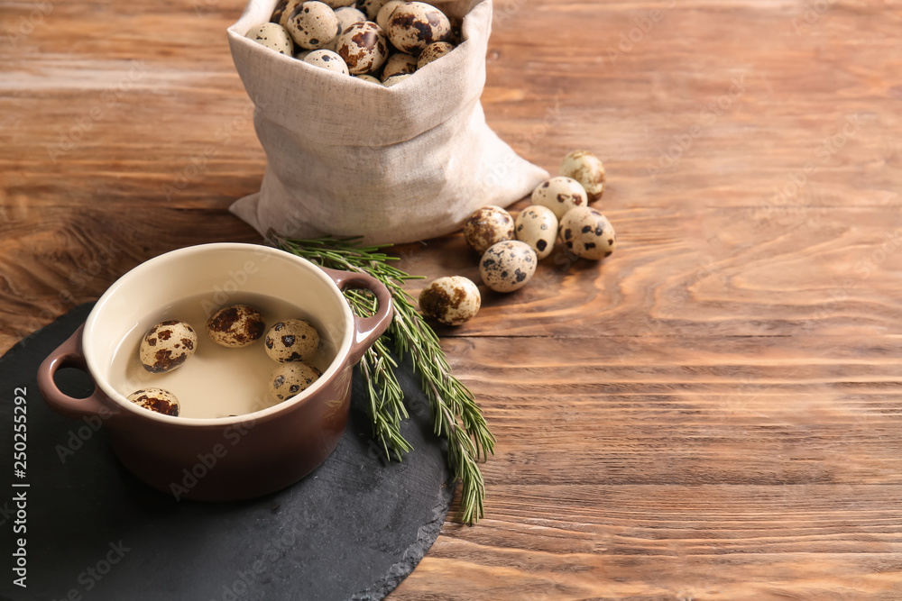 Pot and bag with quail eggs on wooden table