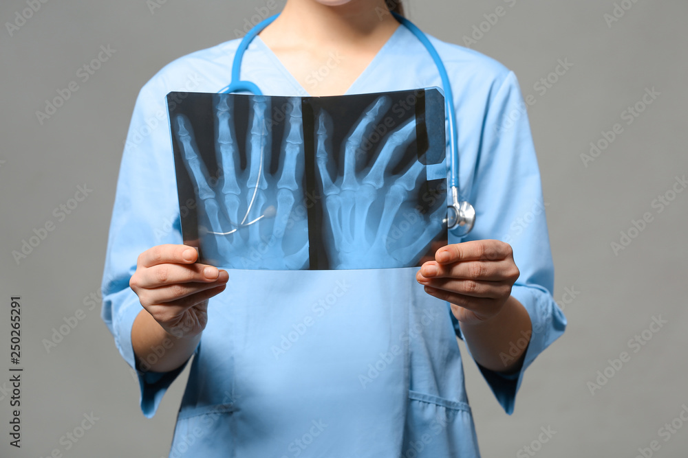 Female doctor studying X-ray image on grey background