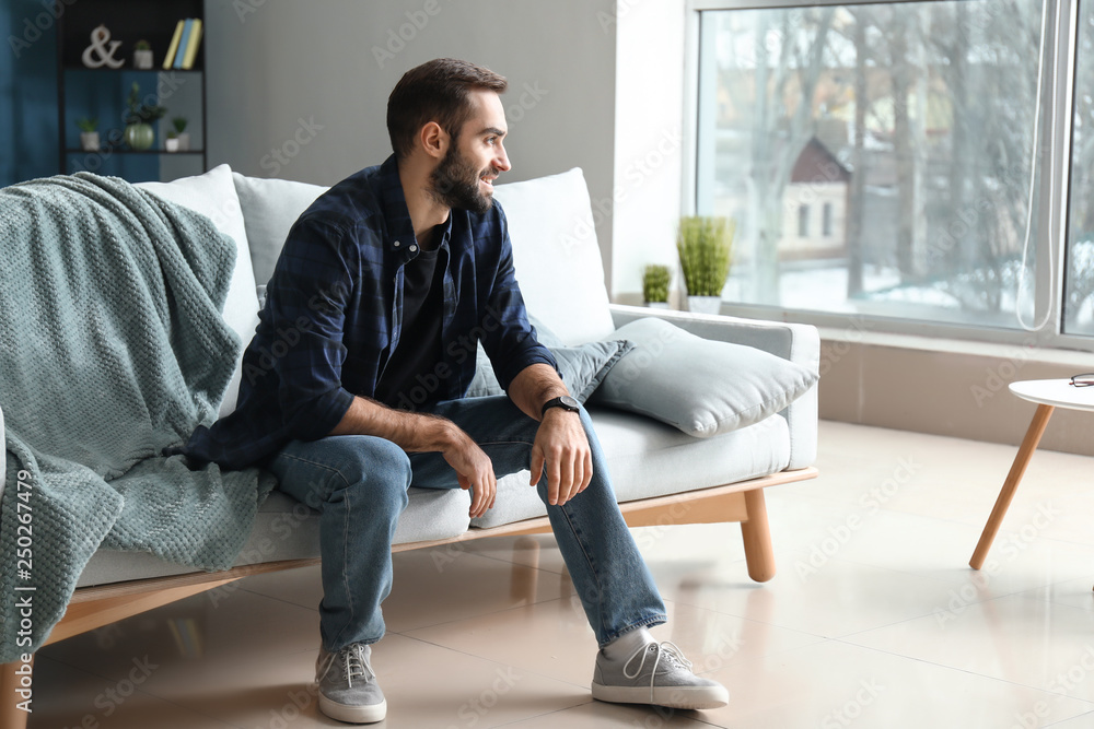 Handsome fashionable man sitting on sofa at home