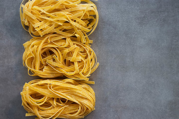 Two types of tagliatelle yellow and green. Egg and spinach noodles on a gray background.