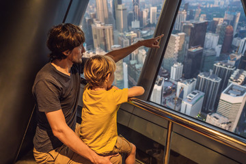 Wall Mural - Dad and son are looking at Kuala lumpur cityscape. Panoramic view of Kuala Lumpur city skyline evening at sunset skyscrapers building in Malaysia. Traveling with kids concept