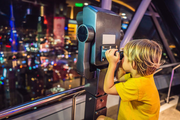 Wall Mural - Little boy looks at Kuala lumpur cityscape. Panoramic view of Kuala Lumpur city skyline evening at sunset skyscrapers building in Malaysia. Traveling with kids concept