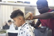 © Aksinia - Boy in the african barbershop. Cute mixed boy makes a haircut in the African salon. Hair style. Haircut by machine for children. School boy hair style.