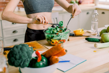 Woman cooking in new kitchen making healthy food with vegetables. Young Caucasian woman in her twenties