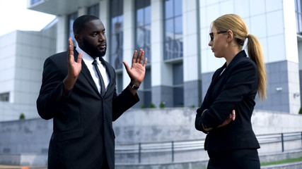 Female boss offending afro-american employee, man trying to justify his doings