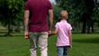 © motortion - Dad and boy holding hands, walking away, parenting and friendship, happy family