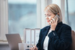 © Suteren Studio - Young woman talking on a cellphone in her office