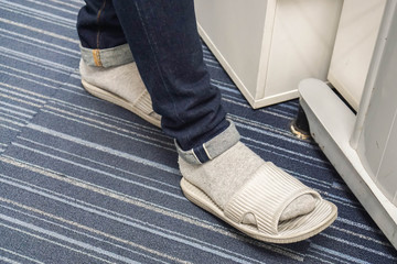 close up man with dark blue jeans wear grey slippers with socks in office