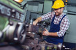 © zorandim75 - Worker in uniform operating in manual lathe in metal industry factory.