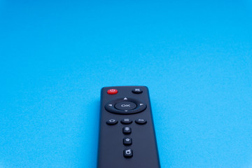 Remote control TV or radio isolated on blue background with selective focus and crop fragment