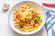 Pasta with shrimps, parsley and chilli peppers on a plate, on a light wooden background - traditional Mediterranean linguine with seafood, Italian cuisine.