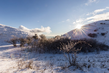 Subasio mountain (Umbria, Italy) in winter, covered by snow, with plants and sun