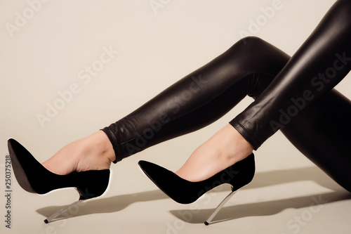 Cuadros en Lienzo Women's legs in black tight-fitting leather trousers and high-heeled shoes sits
