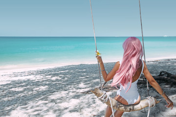 Wall Mural - Girl with pink hair hanging on swing at beach