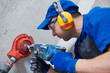 © Kadmy - electrician at work. boring hole for electric outlet by power tool drill.