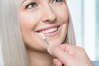 Using a shade guide at womans mouth to check veneer of tooth crown