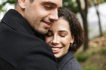 Canvas Print - Portrait closeup of happy people man and woman 20s hugging, while walking through green park