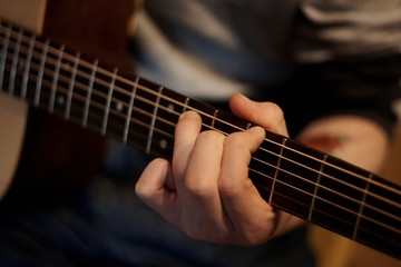 Wall Mural - A person performs a melody on an acoustic guitar, holding a hand chord on the fretboard