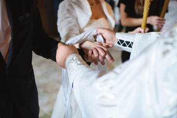 priest tying hands of bride and groom